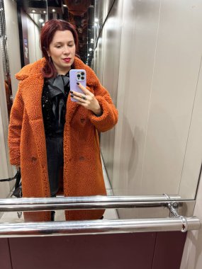 Modern asansör kabininde aynalı selfie çeken bir kadın. Kentsel yaşam tarzı anı, kişisel tarz ifadesi, günlük rutin, kişisel algılama ve yansıtıcı iç mekan aracılığıyla çağdaş hareketlilik