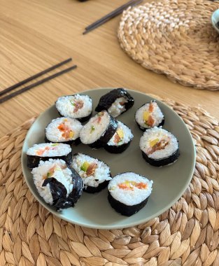 Yemek masasında servis edilen ev yapımı suşi ruloları. Japon mutfağı, ev yemeği, dengeli beslenme, yemek hazırlama, günlük yemek ritüeli, basitlik ve taze ev yapımı yemeklerin keyfi..