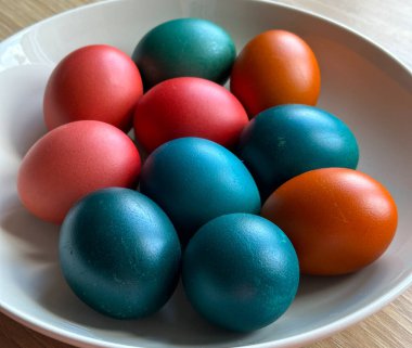 Renkli Paskalya yumurtaları gün ışığında tabağa dizilmiş. Tatil geleneği, mevsimlik kutlama, aile ritüeli ve dekoratif gıda tasarımı..