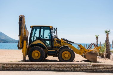 Deniz kenarındaki bir gezinti güvertesine yerleştirilmiş inşaat makineleri. Sahil bakımı, kentsel kalkınma ve turizm altyapısı ile doğal çevre arasındaki denge