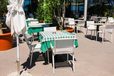 Açık terasta yeşil masa örtülü bir kafe masası. Günlük yemek ritüelleri, rahat servis atmosferi, ve basit konukseverlik estetiği yavaş zevki teşvik ediyor.