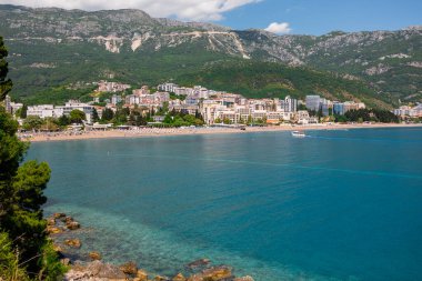 Karadağ 'ın dağları ve kıyı şeridi olan kıyı kenti manzarası. Kentsel gelişim, doğal manzara entegrasyonu ve dengeli kıyı yaşamını şekillendiren deniz kenarı yaşam tarzı
