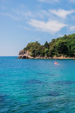 Rocky kıyı şeridi canlı turkuaz denizle buluşuyor. Kıyı manzarası, yaz doğası ve sakin açık hava keşfi.