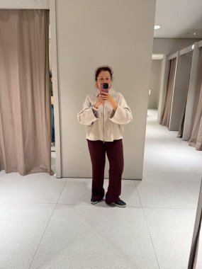 Deneme odasında montunu ayarlayan kadının yakın çekimi. Moda ve minimalist zarafetin dokunsal algısı ile dokunun keşfi, öz farkındalık ve kimlik