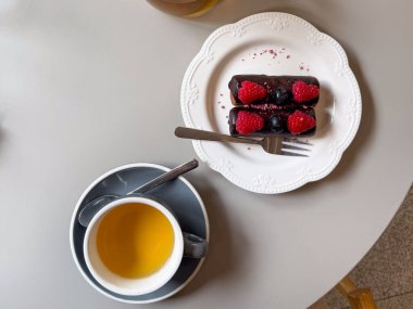 Masasında böğürtlen olan çay ve çikolatalı tatlı manzarası. Kafe hayatında rahat duraklama, rahatlama ve rahatlama.