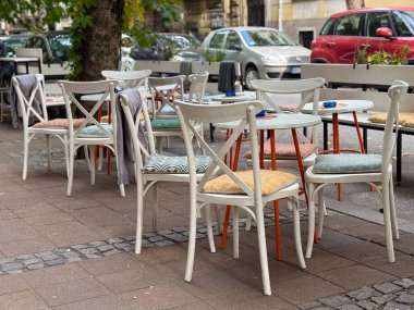 Şehir caddesinde renkli sandalyeleri ve boş masaları olan bir açık kafe terası. Kentsel yaşam tarzı, rahatlık ve günlük basitlik rahat bir sosyal çevrede
