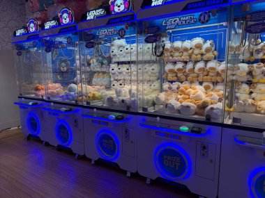 Belgrad, Sırbistan, 12 Haziran 2025. Renkli pelüş oyuncaklarla dolu parlak atari makineleri bir alışveriş merkezinde neon ışıkların altında parlıyor..