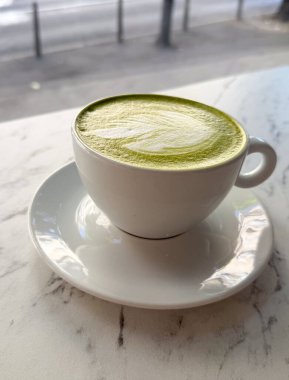 Daire üzerinde beyaz seramik bardakta kibrit latte. Japon çay kültürü, sağlıklı yaşam tarzı ve modern kafe eğilimi