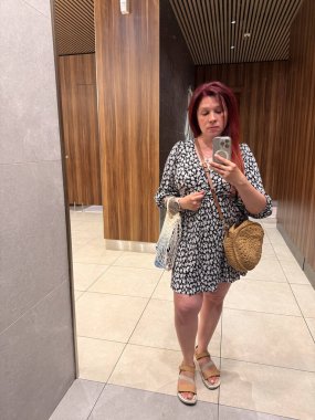 Asansör aynasında saman çantalı selfie çeken bir kadın. Moda, yaz tarzı ve yaşam tarzı kimliği..