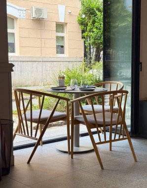 Sandalyeli ve camlı ahşap bir yemek masası bir kafenin penceresinin yanında duruyor. Konukseverlik, yaşam tarzı ve eğlence kentsel yemek kültürü ve sosyal atmosferi yansıtıyor