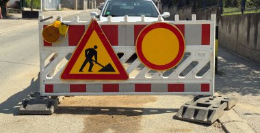 Yol inşaatı bariyeri ve trafik uyarı levhaları caddeyi güvenlik için kapatıyor. Önleme, ihtiyat ve kamu hizmetini temsil eden altyapı, düzenleme ve kentsel yönetim