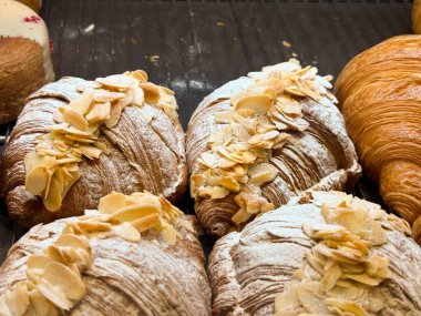 Fırın tepsisinde şekerle tozlanmış badem kruvasanları. Bir pastanede zanaatkar pastası, fındık sosu ve kahvaltıya düşkünlük..
