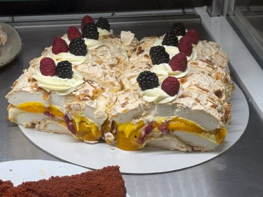 Kremalı kremalı ve tropikal meyveli pasta sergileniyor. Katmanlı tatlı kompozisyonu yoluyla bozulma, kutlama ve el yapımı pasta kültürü.