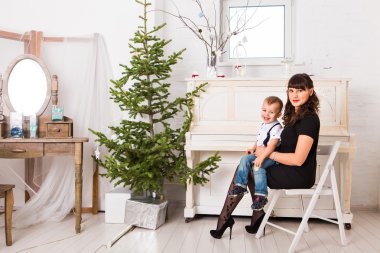 Anne ve oğlu Noel için dekore edilmiş bir köknar ağacının yanında iskambil