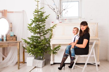 Anne ve oğlu Noel için dekore edilmiş bir köknar ağacının yanında iskambil