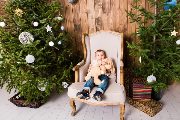Menino sentado na cadeira perto da árvore de Natal — Fotografia de Stock