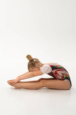 Koklear implantı olan ritmik jimnastikçi çocuk ileri germe pozu veriyor. Rehabilitasyon terapisi, koklear implantasyon, kapsayıcı spor, duyusal entegrasyon ve çocukluk motor öğrenimi..