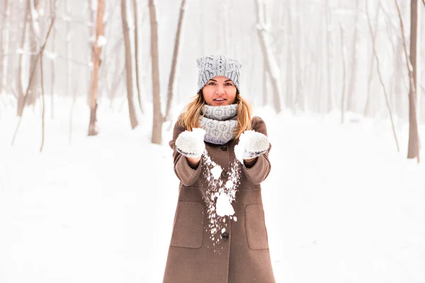 Девушка играет со снегом в парке — стоковое фото