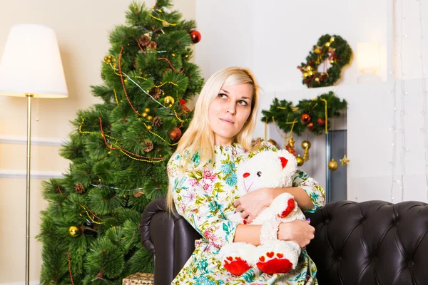 Frau mit Teddybär unterm Weihnachtsbaum im Zimmer — Stockfoto
