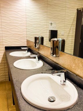 Modern tuvalette aynalı ve fayanslı duvarlı üçlü lavabo tezgahı. Konfor, düzen ve misafir servisi için temizlik, hijyen ve işlevsel konukseverlik tesisi