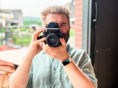 Kamera tutan ve restoran penceresinin yanında fotoğraf çeken bir adam. Fotoğraf, yaratıcılık ve yaşam tarzı etkinliği eğlence ve konukseverlik ortamında yakalanır.