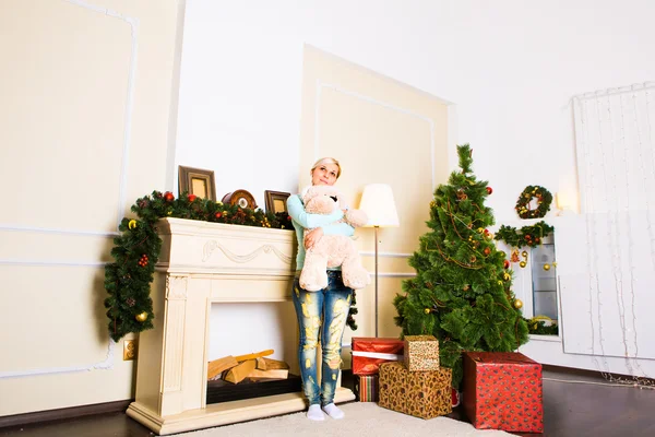 Junge Frau am Kamin in weihnachtlich dekoriertem Haus — Stockfoto