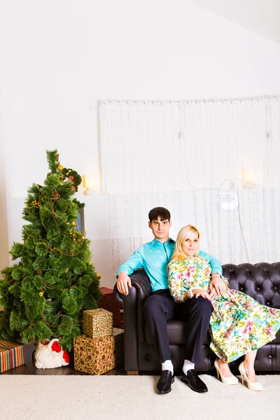 Dos hombres y mujeres en sombrero de santa decorando un nuevo árbol de