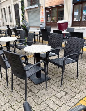 Boş kafeterya masaları ve sandalyeler sessiz bir şehir ortamında. Günlük yaşamda şehir rutini, boş zaman ve açık alan.