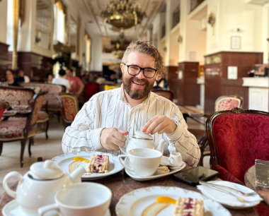 Milenyum adamı klasik dekorlu lüks bir kafede zarif bir çay molası veriyor. Lüks restoran güzel sofra takımı ve bir dilim pasta ile donatılmış, zamansız ve rafine bir atmosfer..