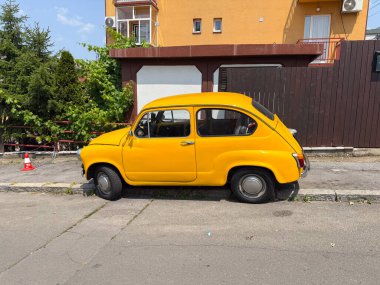 Caddeye park edilmiş klasik sarı bir araba. Klasik otomobil, eski ulaşım ve nostalji.