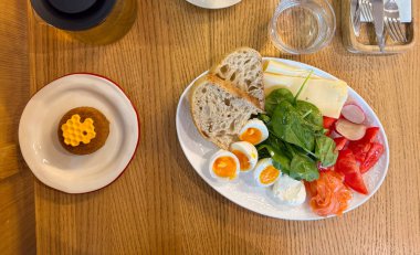 Ballı tatlı, yumurta, sebze, peynir ve ekmek ile sabah yemeği ahşap yüzey manzaralı. Dengeli kahvaltı konforu ve yavaş yaşamı simgeler.