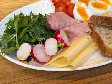 Kahvaltı tabağını peynirli turp yeşilliği ve kaynamış yumurtayla kapat. Yemek ayrıntıları, taze malzemeler, sağlıklı yaşam tarzı, kafe servisi, iştah açıcı kompozisyon..