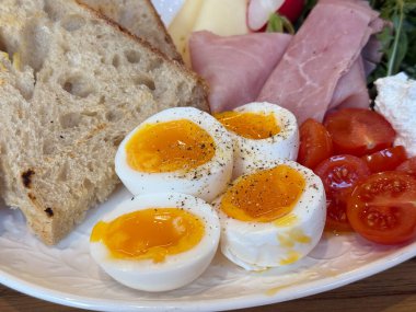 Yumurta kaynatılmış yumurta, yumurta sarısı, ekmek ve domatesle servis ediliyor. Kahvaltı ayrıntıları, taze malzemeler, iştah açıcı kompozisyon, sağlıklı yemek.