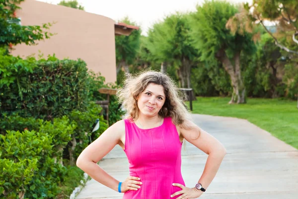 Jonge vrouw in roze jurk poseren op zomer park — Stockfoto