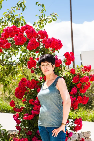 Gelukkige vrouw in de buurt van roze bloemen in de zomer — Stockfoto