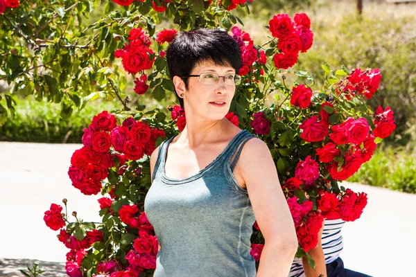 Gelukkige vrouw in de buurt van roze bloemen in de zomer — Stockfoto
