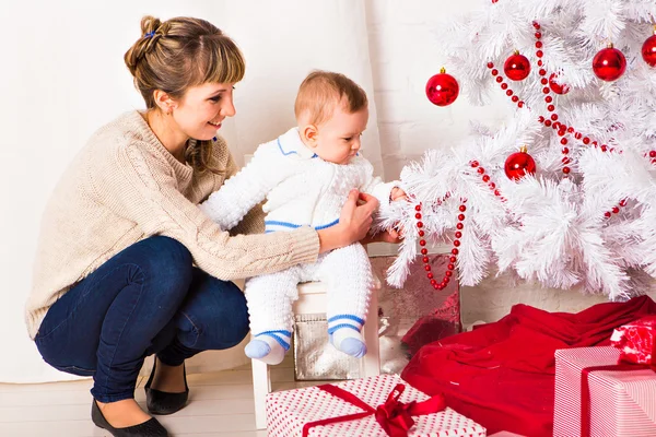 Sorrir jovem mãe com lindo bebê perto da árvore de Natal — Fotografia de Stock