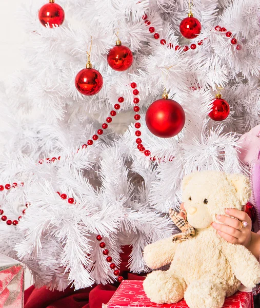 Κορίτσι αγκαλιάζει αρκουδάκι κοντά χριστουγεννιάτικο δέντρο — Φωτογραφία Αρχείου