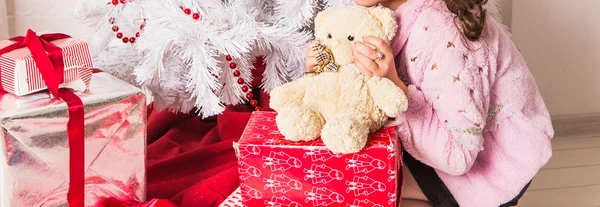 Mädchen umarmt Teddybär in der Nähe von Weihnachtsbaum — Stockfoto