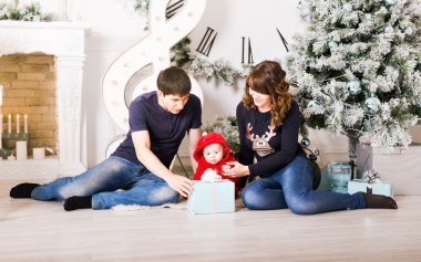 Bebek açılış hediyeleri Noel ailesiyle. Mutlu gülümseyen ebeveyn ve çocuk evde yeni yıl kutlama