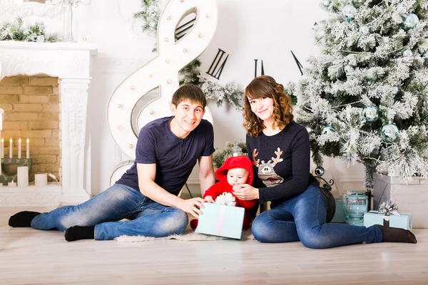 Kerstmis familie met babygiften openen. Gelukkige lachende ouders en kind vieren thuis Nieuwjaar — Stockfoto