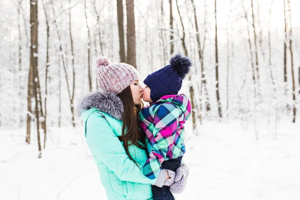 Glad familj mor och barn baby dotter på en vinter promenad i skogen — Stockfoto