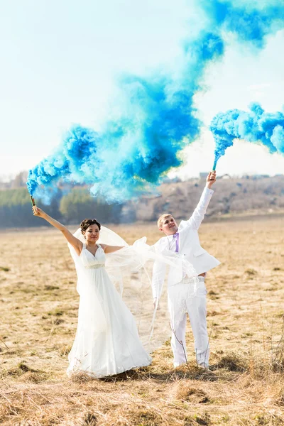 Wedding couple with blue smoke in the park — Stock Photo, Image