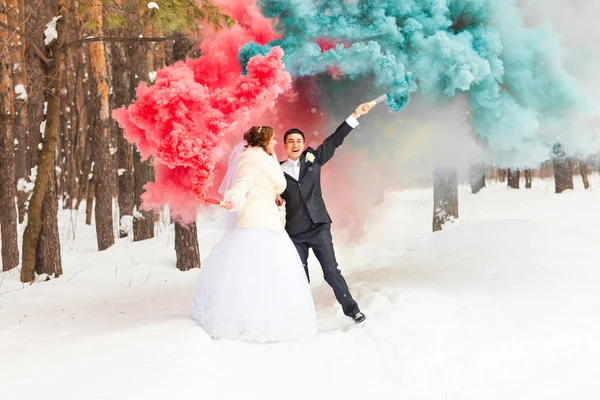 Wedding couple with color smoke in the winter park. Colour bomb — Stock Photo, Image