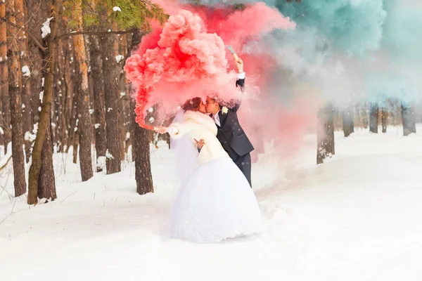 Casamento casal com fumaça de cor no parque de inverno. Bomba de cor — Fotografia de Stock