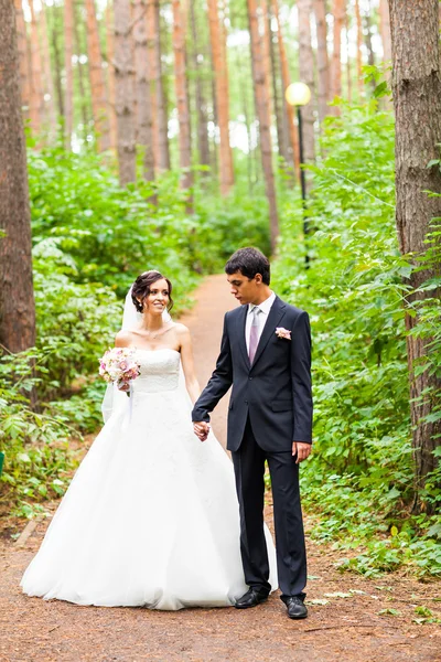 Fiatal esküvői pár gyaloglás együtt a park — Stock Fotó