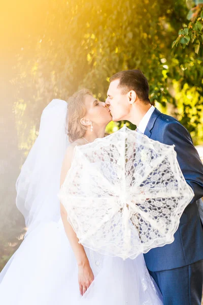 Pareja casada sosteniendo paraguas blanco — Foto de Stock