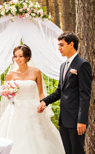 Cheerful married couple standing near the wedding arch — Stock Photo, Image