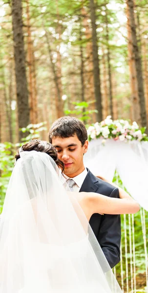 Das Brautpaar umarmt sich in der Nähe des Hochzeitsbogens — Stockfoto