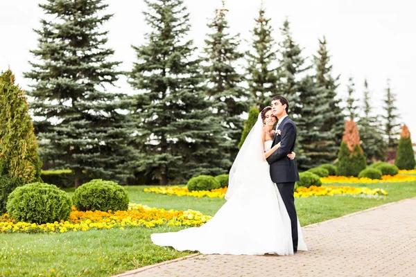 Groom and Bride dans un parc. robe de mariée. Bouquet de fleurs de mariée — Photo